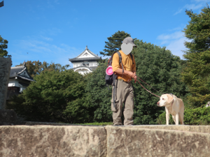 本丸を背景にする犬と人